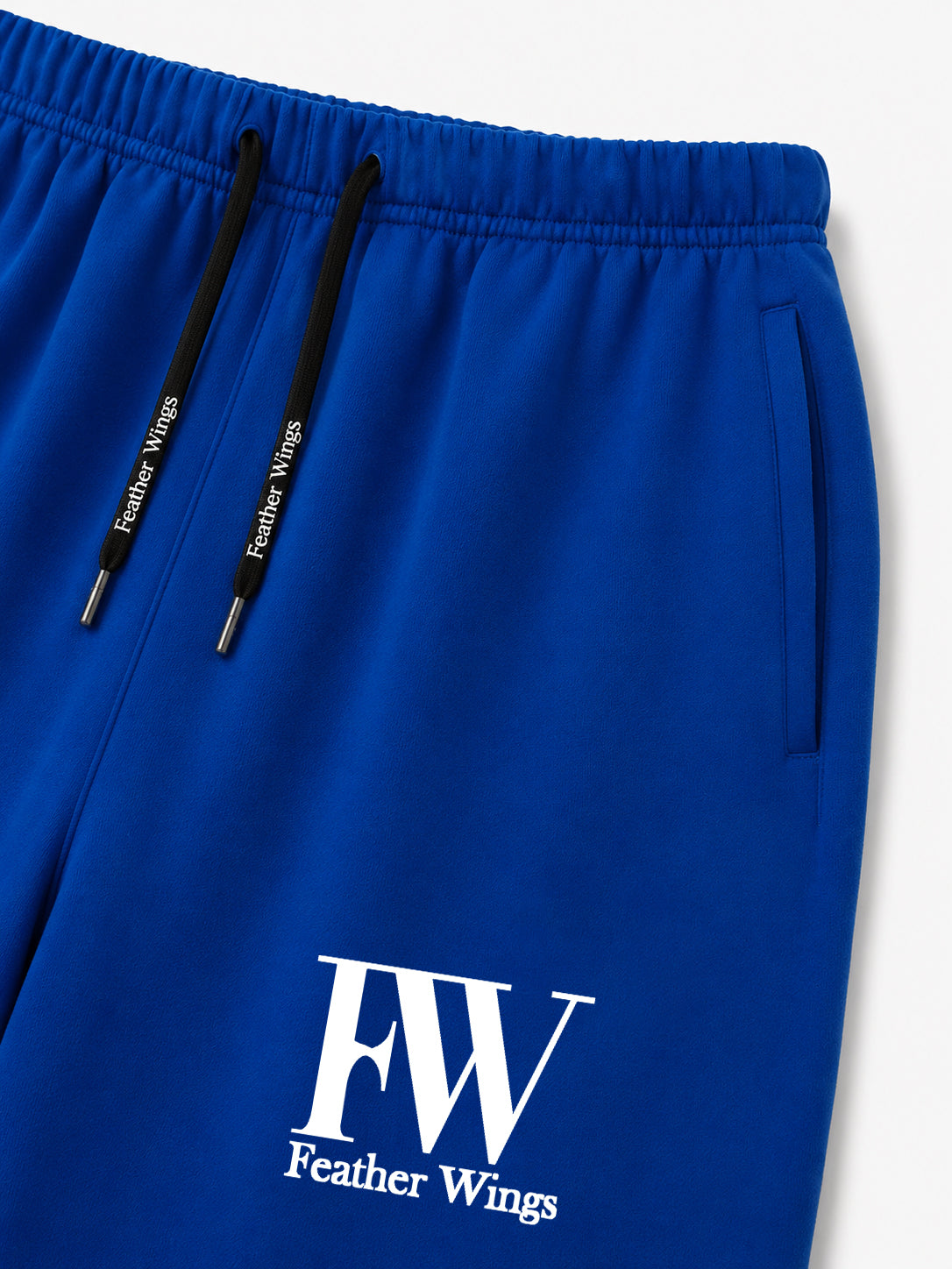 Close-up of royal blue drawstring sweatpants with black drawstrings and a white 'FW Feather Wings' logo printed on the lower left leg, shown against a light gray background.