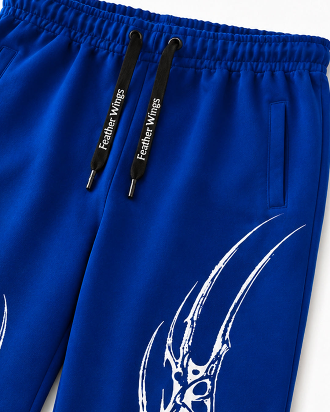 Close-up of royal blue athletic pants with black drawstrings printed with 'Feather Wings' and a large white graphic design on the leg.