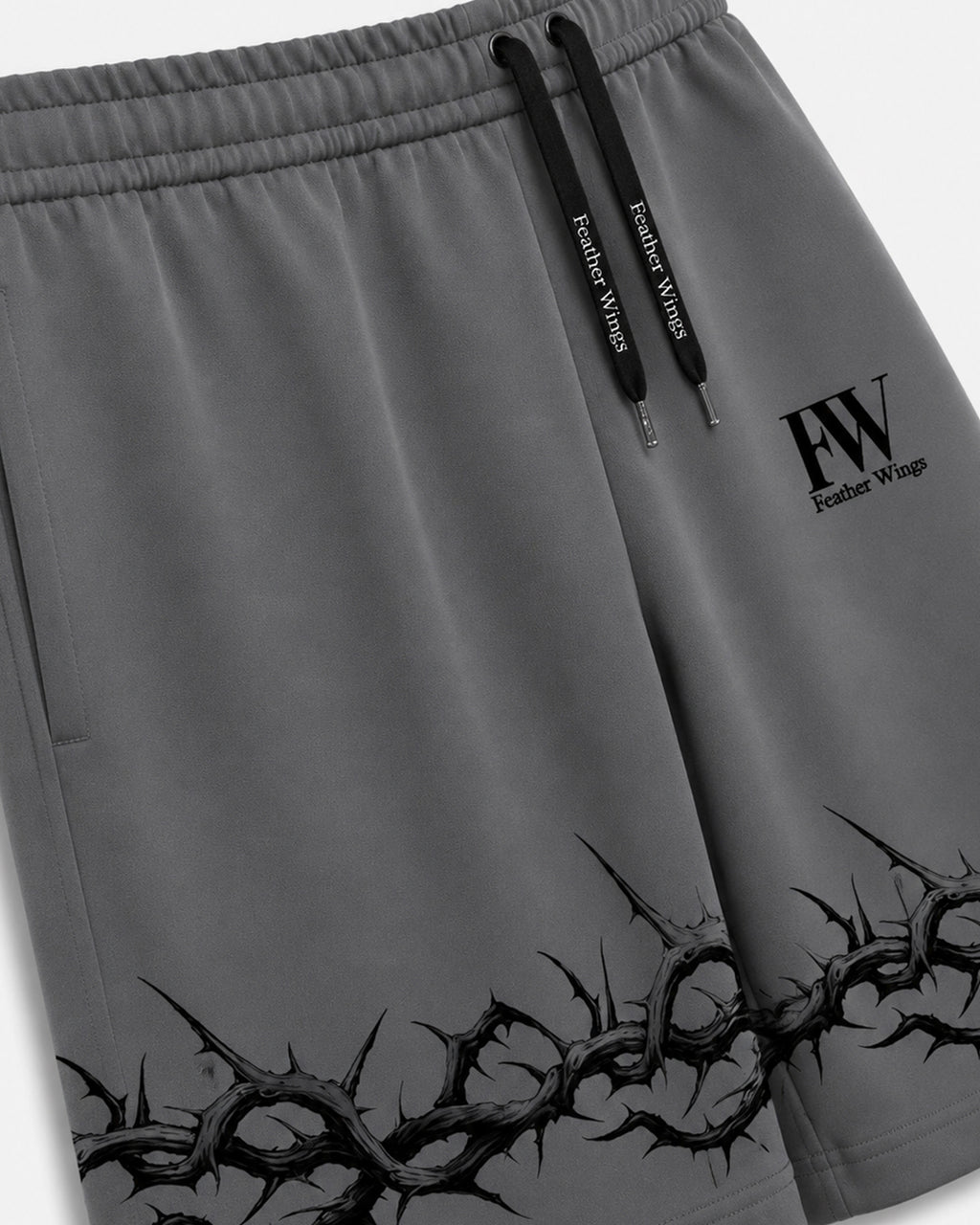 Gray athletic shorts with black drawstrings, a black 'FW Feather Wings' logo on the left thigh, and a black thorny graphic along the bottom hem.
