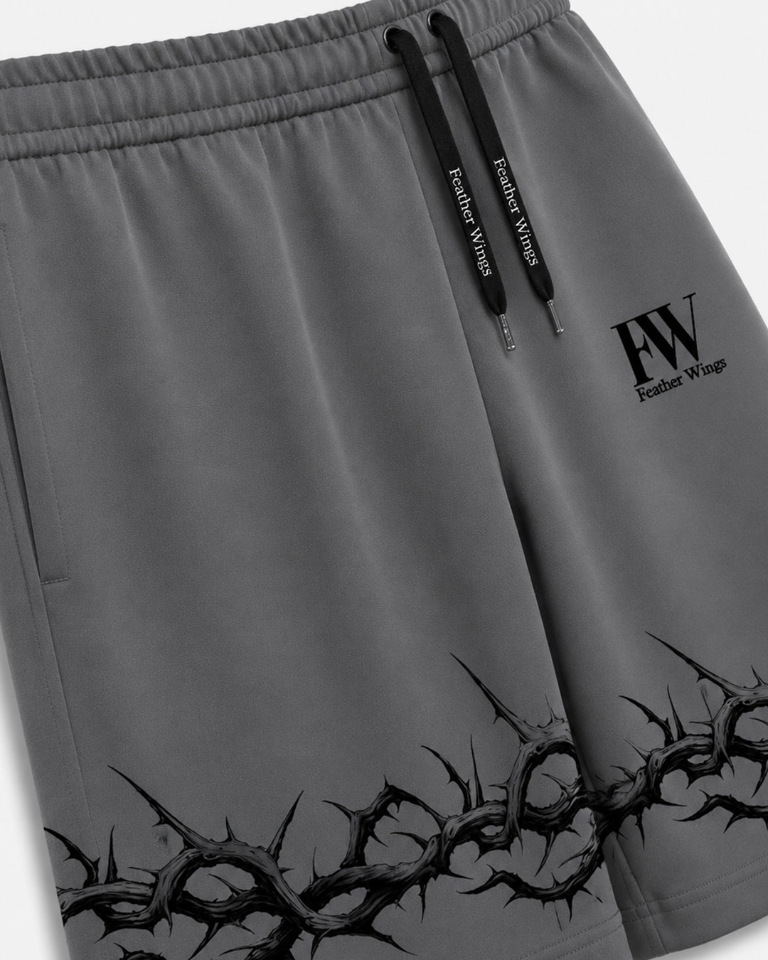 Gray athletic shorts with black drawstrings, a black 'FW Feather Wings' logo on the left thigh, and a black thorny graphic along the bottom hem.